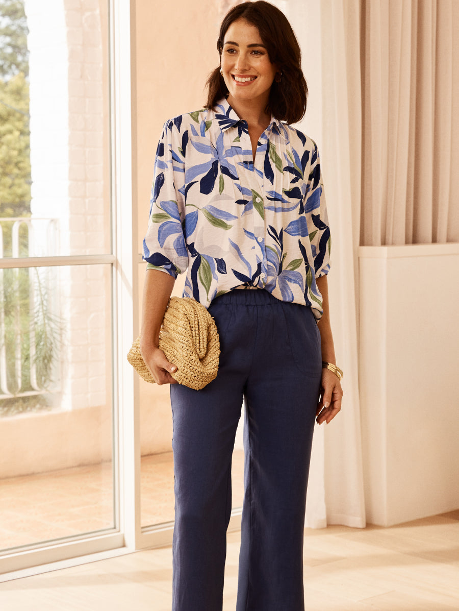 Woman wearing a floral blouse and navy pants indoors