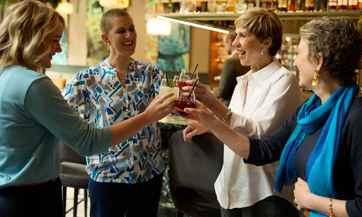 Four women holding drinks in a restaurant setting 
