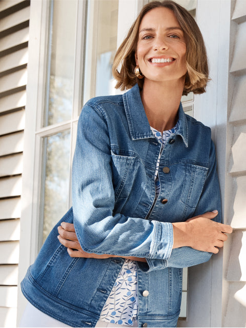 Woman wearing a denim jacket standing outside a house