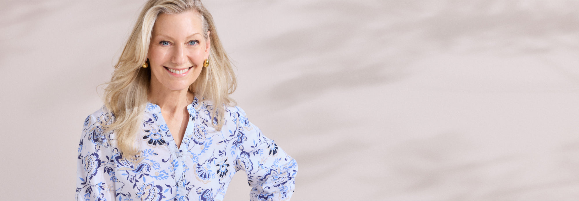 Woman wearing a blue floral blouse against a beige background