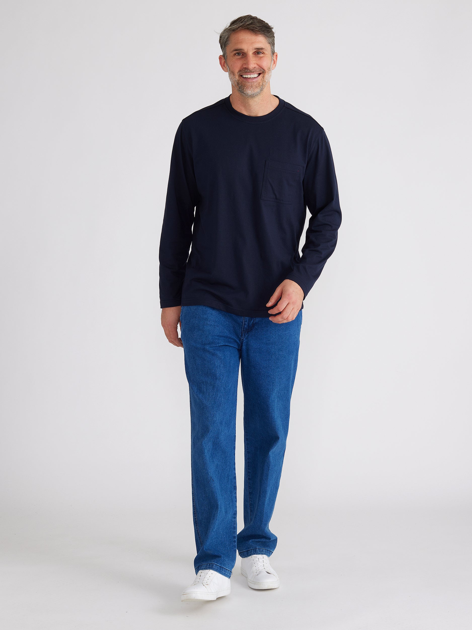 Full length image of model wearing mens ipswich denim jean in denim blue colour and a plain  navy long sleeve top.